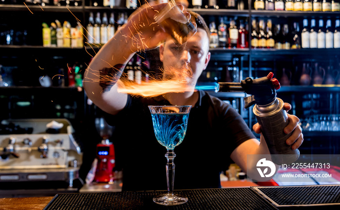 The bartender makes a cocktail with a fire show at the bar. Bartender at work.