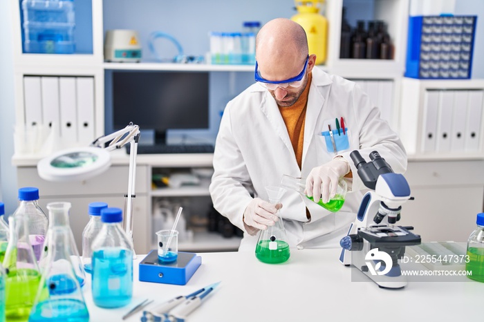 Young man scientist measuring liquid at laboratory