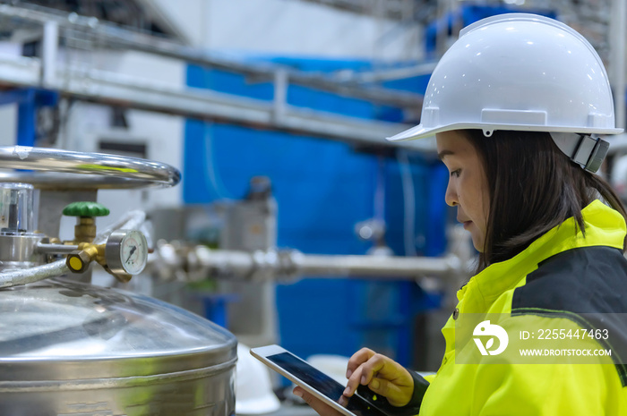 Asian engineer working at Operating hall,Thailand people wear helmet  work,He worked with diligence and patience,she checked the valve regulator at the hydrogen tank.