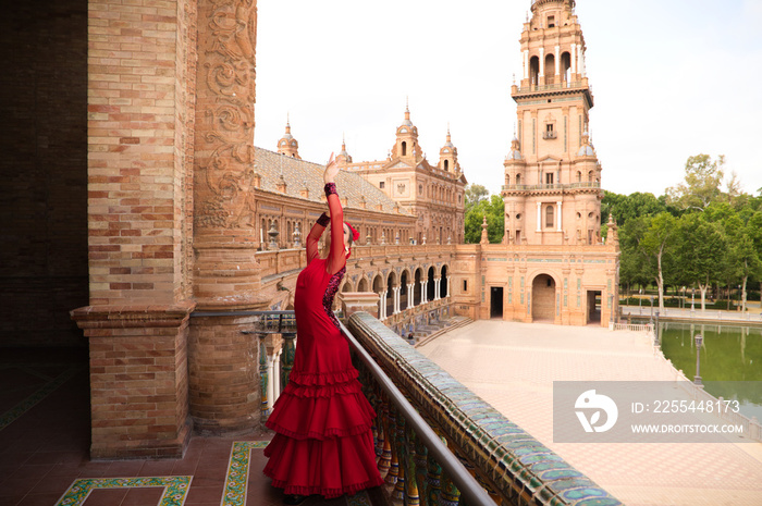 Beautiful teenage woman dancing flamenco in a square in Seville, Spain. She wears a red dress with ruffles and dances flamenco with a lot of art. Flamenco cultural heritage of humanity.