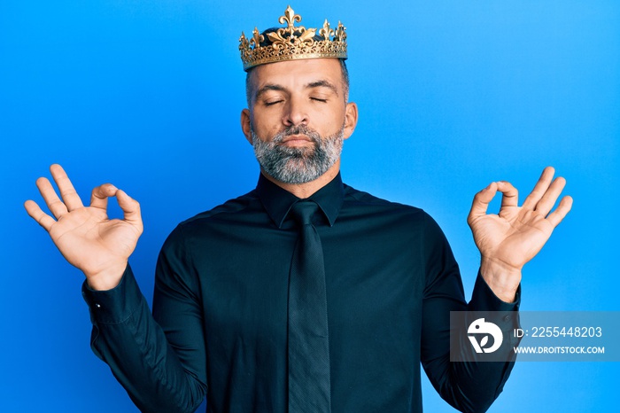 Middle age handsome business man wearing king crown relax and smiling with eyes closed doing meditation gesture with fingers. yoga concept.