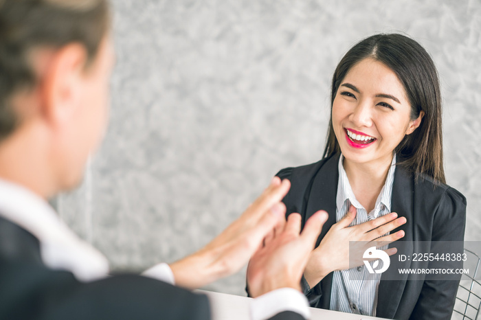 Boss/Business man employer admires young Asian business woman/staff/employee by thumb up and clap with smiling face for her success and good/best in work and recognition/appreciate.