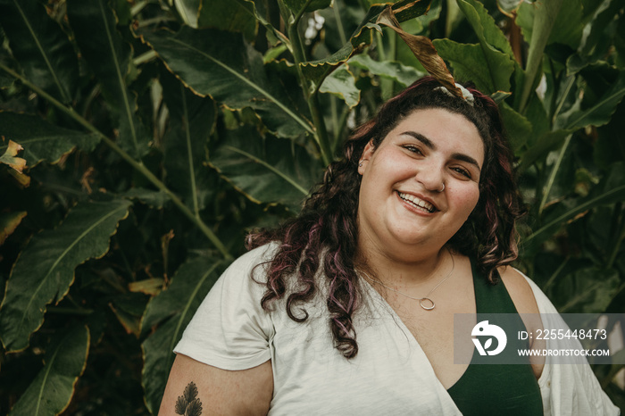 closeup of a plus size jewish woman smiling in front of plants