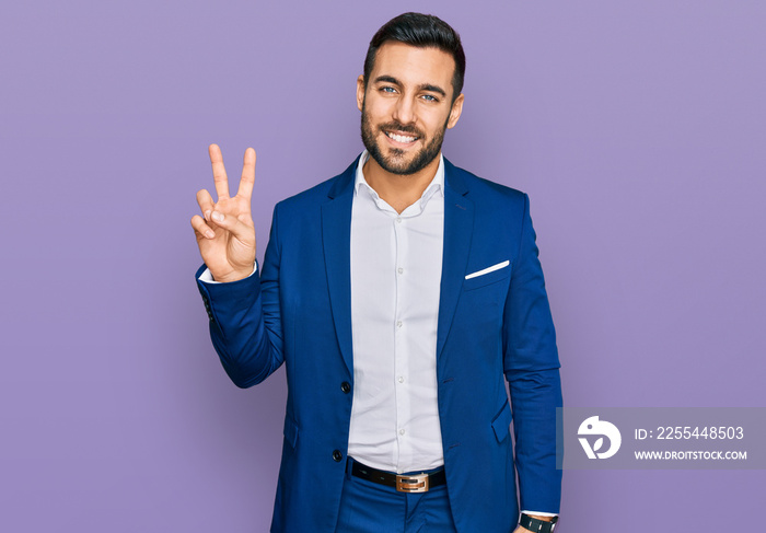 Young hispanic man wearing business jacket smiling looking to the camera showing fingers doing victory sign. number two.