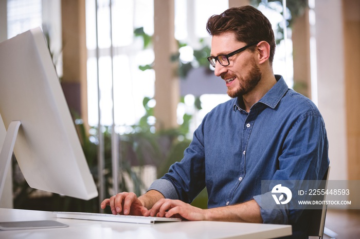 Happy businessman working on computer at creative office