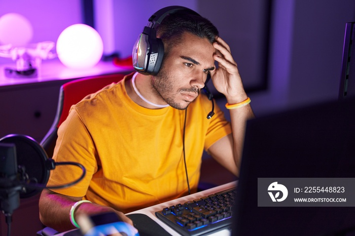 Young hispanic man streamer stressed using computer at gaming room