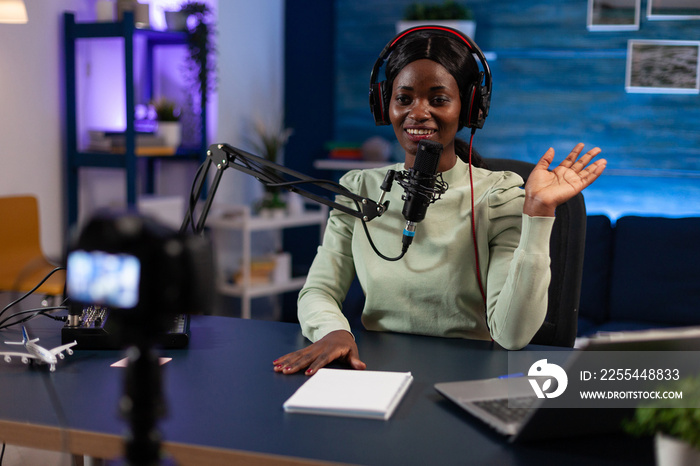 Social media woman creator greeting subscribers while recording video content for youtube channel. Influencer sitting in podcast studio filming tutorial using production equipment. On air talk show