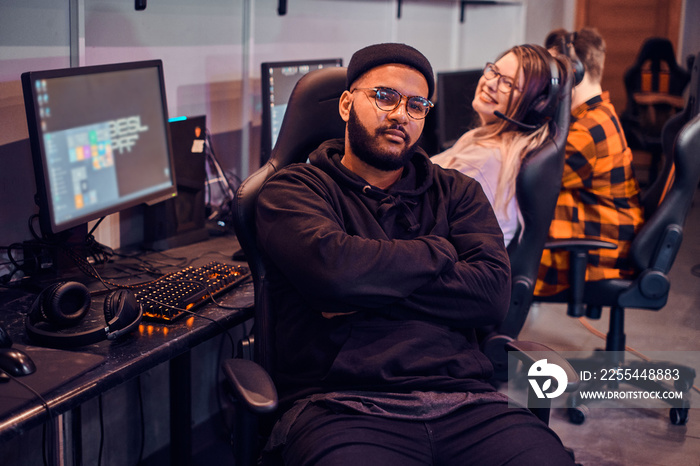 Gamer in glasses is sitting on chair while pretty girl behide his back is smiling to the camera.