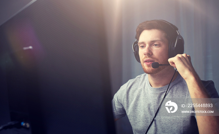 man in headset playing computer video game at home