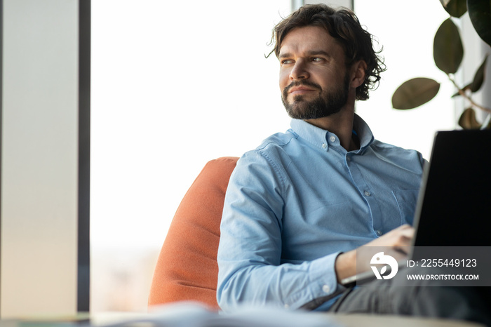 Businessman using laptop sitting on bean bag in office