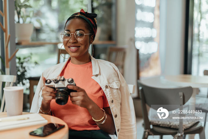 Smiling young afro-american woman with photo camera