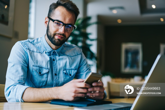 Positive man using smartphone in cafe