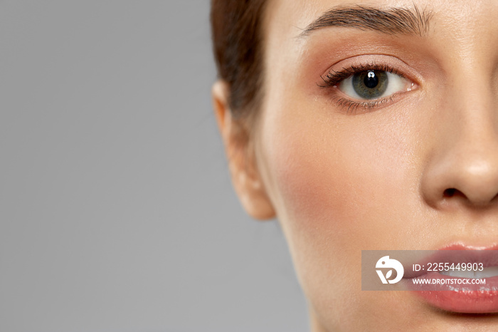 beauty, makeup and vision concept - close up of beautiful young woman face and eyes over grey background