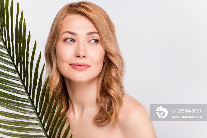 Portrait of attractive woman with leaves smooth flawless clean clear skin looking aside copy space isolated grey color background