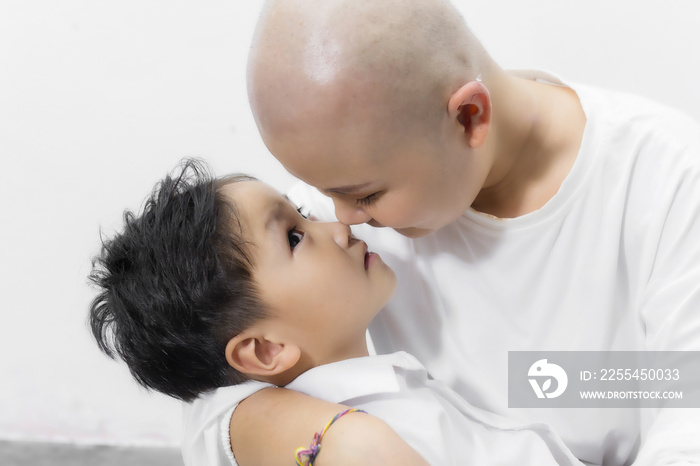 Young adult female cancer patient spending time with son at home, relaxing on the couch. Cancer and family support concept.