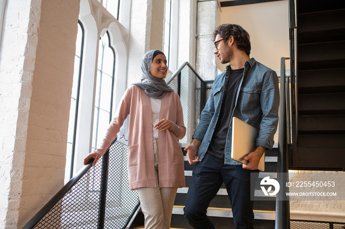 Woman wearing headscarf and man talking on steps