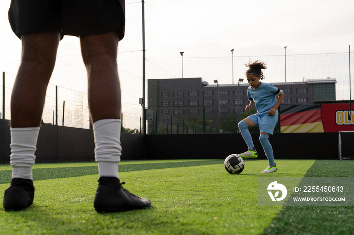 Man and girl (6-7) playing soccer on soccer field