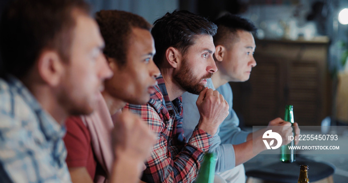 Young company of cheerful multi-race friends meeting at home together watching football game cheering for favorite team on TV.