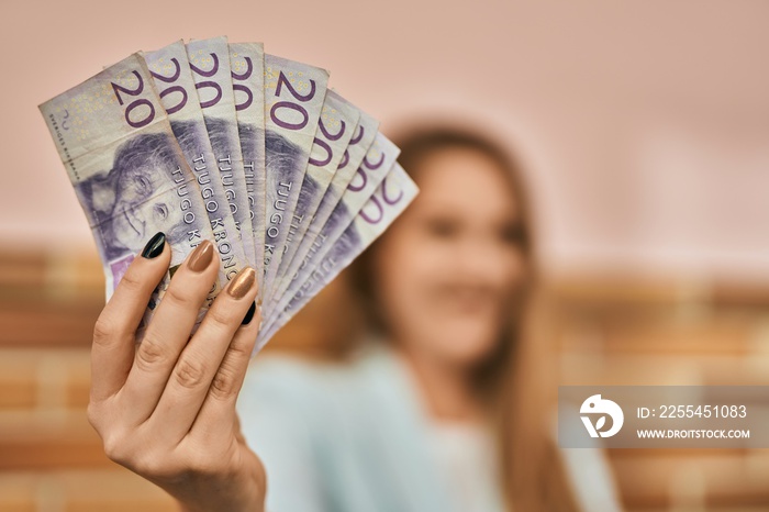 Young blonde businesswoman smiling happy holding sweden krona banknotes at the city.