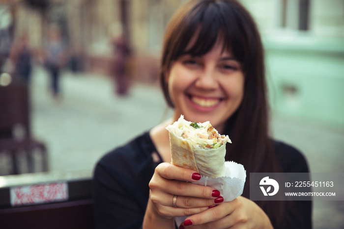 young smiling woman eating fast food outdoors