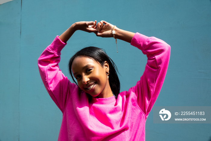 Portrait of smiling young woman holding arms up