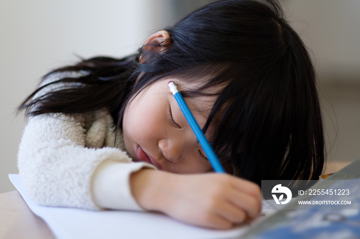 Asian young child girl fall asleep while studying on table with books