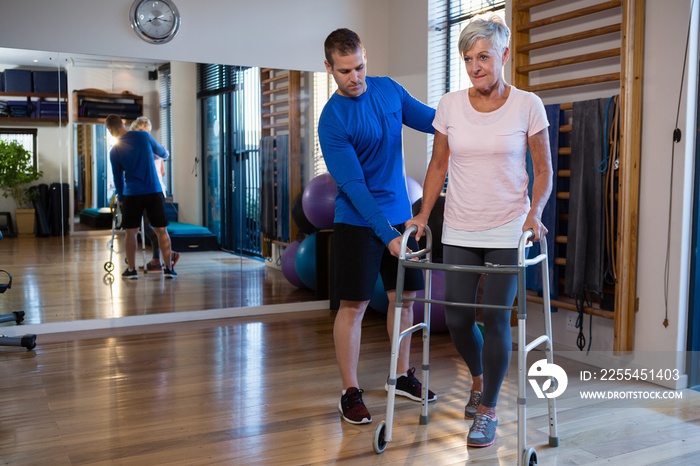 Physiotherapist assisting senior woman patient to walk with