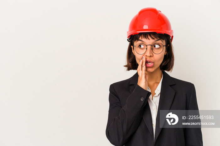 Young architect woman with red helmet isolated on white background is saying a secret hot braking news and looking aside