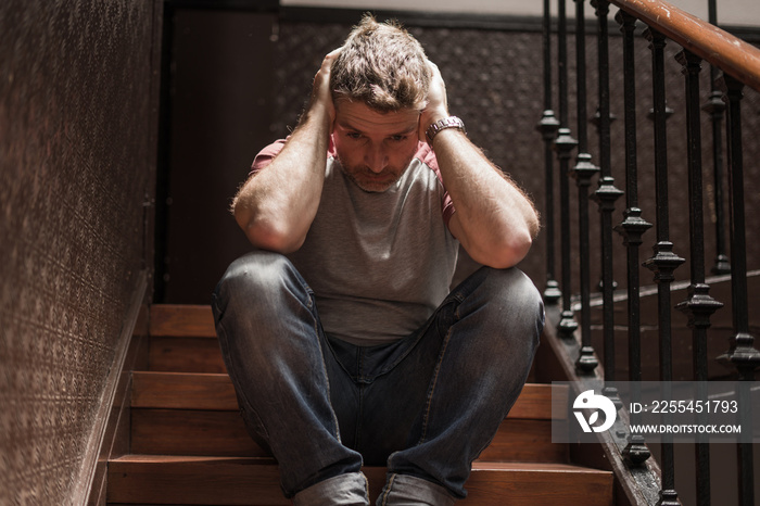 unemployment and divorce - dramatic lifestyle portrait of sad and depressed man on his 40s sitting indoors on staircase thoughtful and worried suffering depression problem