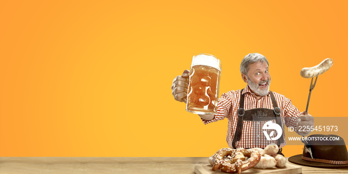 Delighted senior man with beer dressed in traditional Austrian or Bavarian costume holding mug of beer at pub or studio. The celebration, oktoberfest, festival, drinking concept. Flyer with copyspace.