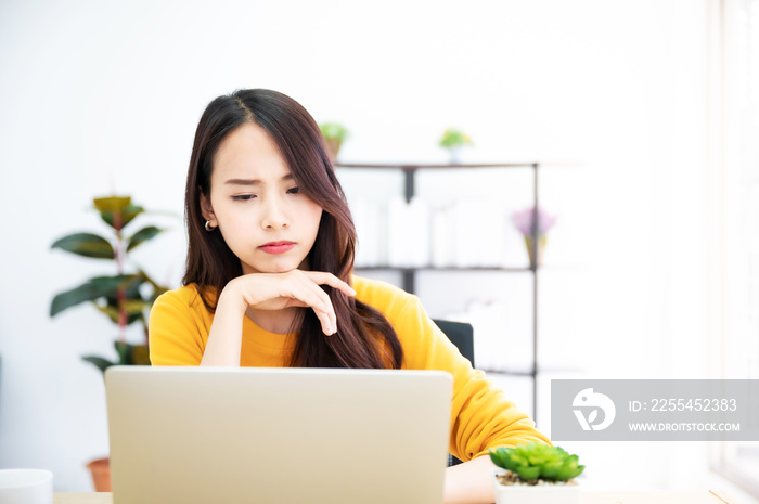 Asian young woman seriously working on computer laptop in house. She thinking find solution problem of work