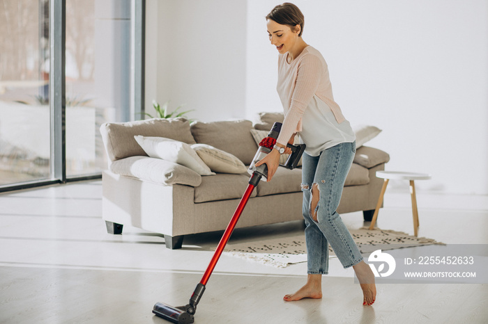 Young woman with rechargeable vacuum cleaner cleaning at home