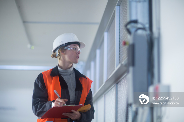 Technikerin mit Helm überprüft Geräte