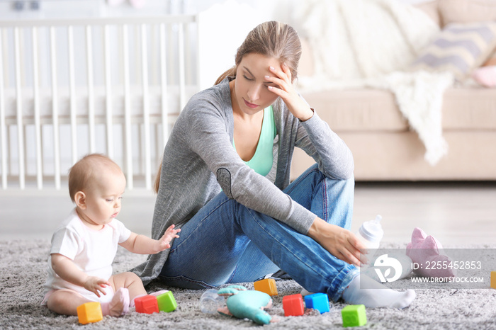 Depressed young woman with cute baby at home