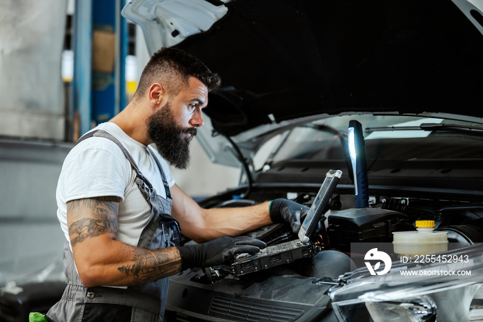 An auto-mechanic in workshop repairs car