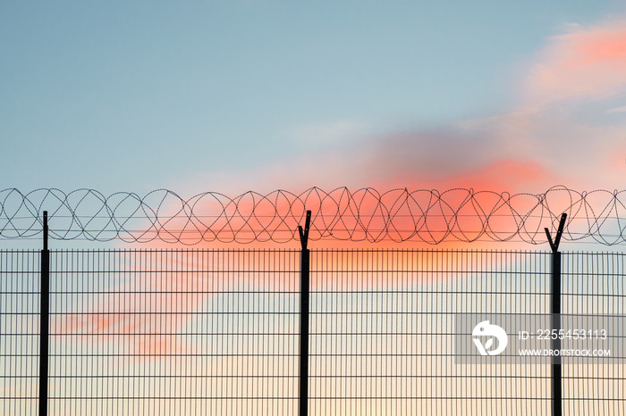 Wire mesh fence with colorful sky background.