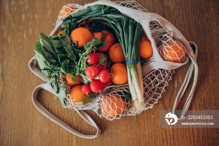 Fresh fruits and vegetables in the string bag on the wooden table