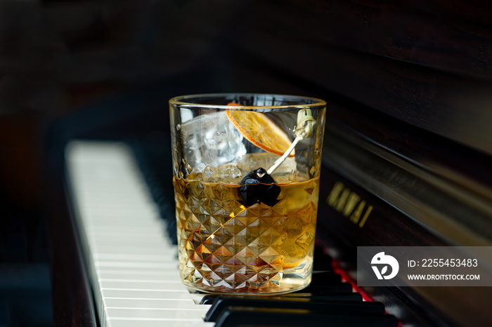 Old fashioned cocktail with orange and cherry on the piano keys.