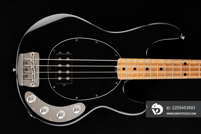 Body of a black electric bass guitar on black background