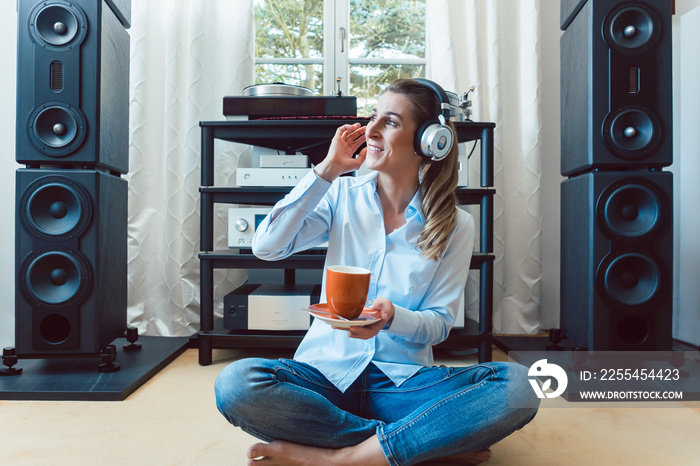 Woman listening to music from a Hi-Fi stereo at home