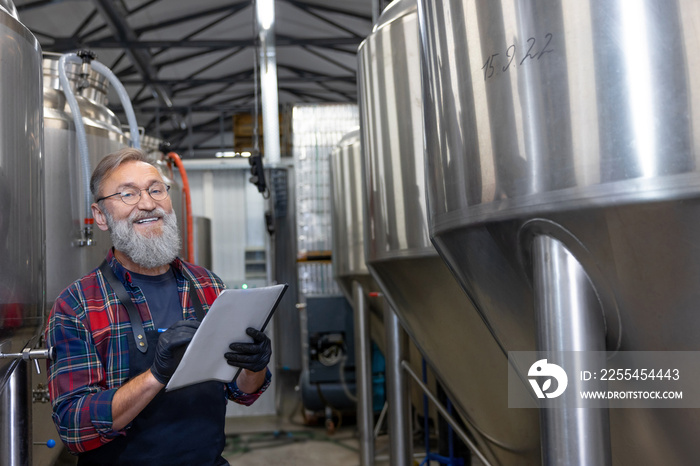 Man in plaid shirt checnking the tanks with beer at the brewery