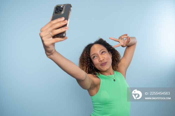 Woman posing to smartphone, showing peace sign