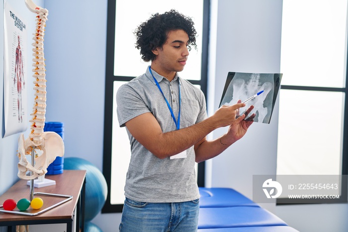 Young hispanic man physiotherapist looking xray at rehab clinic