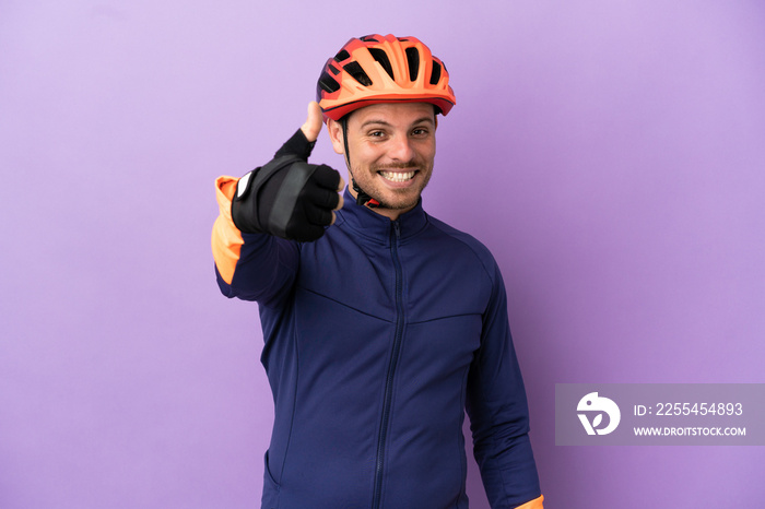 Young Brazilian cyclist man isolated on purple background with thumbs up because something good has happened