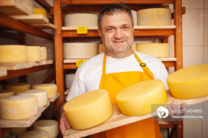 Cheese seller in store, home production, business, entrepreneur. Smiling man, portrait. Businessman, sale of cheese products. Made with love and care. holds in his hands
