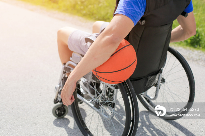 Disabled young basketball player on a wheelchair holding ball and beeing active in sport