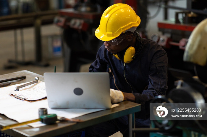 Manufacturing Factory black male Mechanical Engineer Works on Personal Computer at Metal lathe industrial manufacturing factory. Engineer Operating lathe Machinery. American African people.