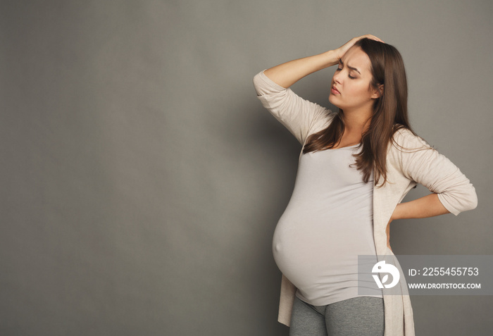 Young pregnant woman with headache at studio