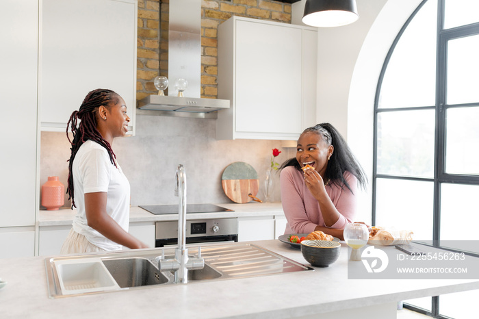 Lesbian couple chatting and eating in kitchen