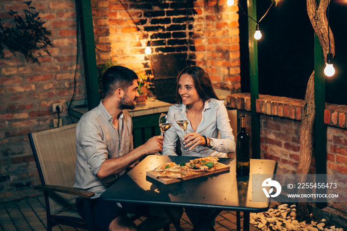 happy couple making toast, while eating pizza outdoor in backyard